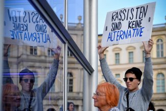In the foreground on the right is a young demonstrator with the slogan: Rassisten sind keine alternative. On the left you can see his reflection in the mirror.