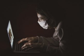 A person wearing a protective mask while using a laptop computer 