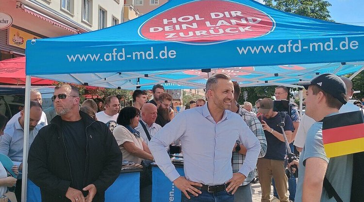 Ulrich Siegmund stoi pod niebieskim namiotem AfD z hasłem „Hol dir dein Land zurück” podczas kampanii wyborczej w Magdeburgu, Saksonia-Anhalt, 2026.