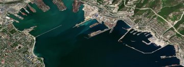 Widok satelitarny z lotu ptaka na port w Noworosyjsku – widoczne nabrzeża, doki, terminale przeładunkowe oraz przybrzeżna zabudowa miejska.