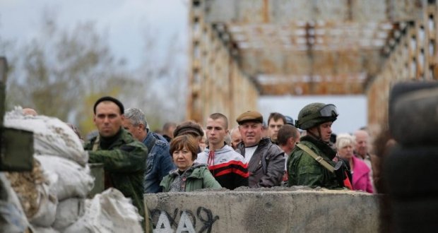 In the picture local ukrainian people and two soldiers on military post on the bridge